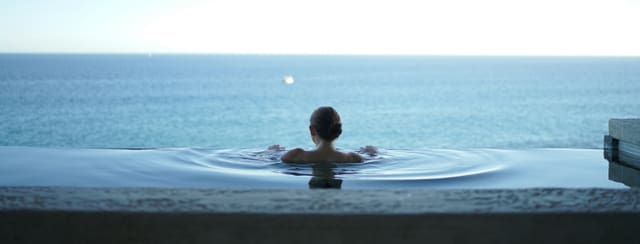 A guest relaxing in an infinity pool overlooking the ocean at Solara